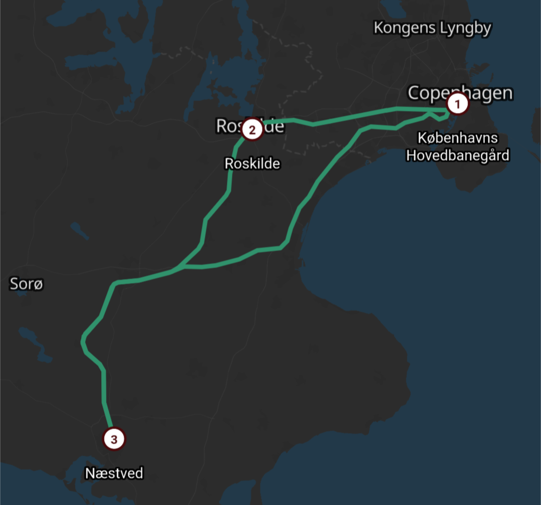 Eit digitalt kart i mørke fargar som viser reiseruta for ein tur på Sjælland i Danmark. Kartbakgrunnen har ein mørkegrå farge for land og mørkeblå for hav. Ei samanhengande, lysegrøn linje markerer ruta som bind saman tre hovudstopp, markert med raude sirklar med kvite tal inni. Ruta startar ved Københavns Hovedbanegård (merka med talet 1) og går vestover til Roskilde (merka med talet 2). Derfrå svingar ruta sørover i ein boge ned til Næstved (merka med talet 3), før ho svingar nordaustover igjen og går i ei meir direkte linje over landskapet tilbake til København, noko som formar ein trekantliknande reiserunde.