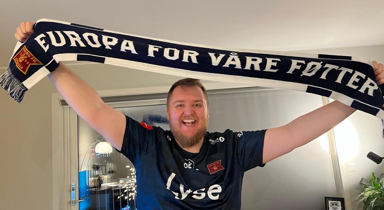 Mann (@markus@skvip.lol) i drakta til Viking FK, han smilar stort og held eit Viking-skjerf over hovudet. På skjerfet står det: Europa for våre føtter