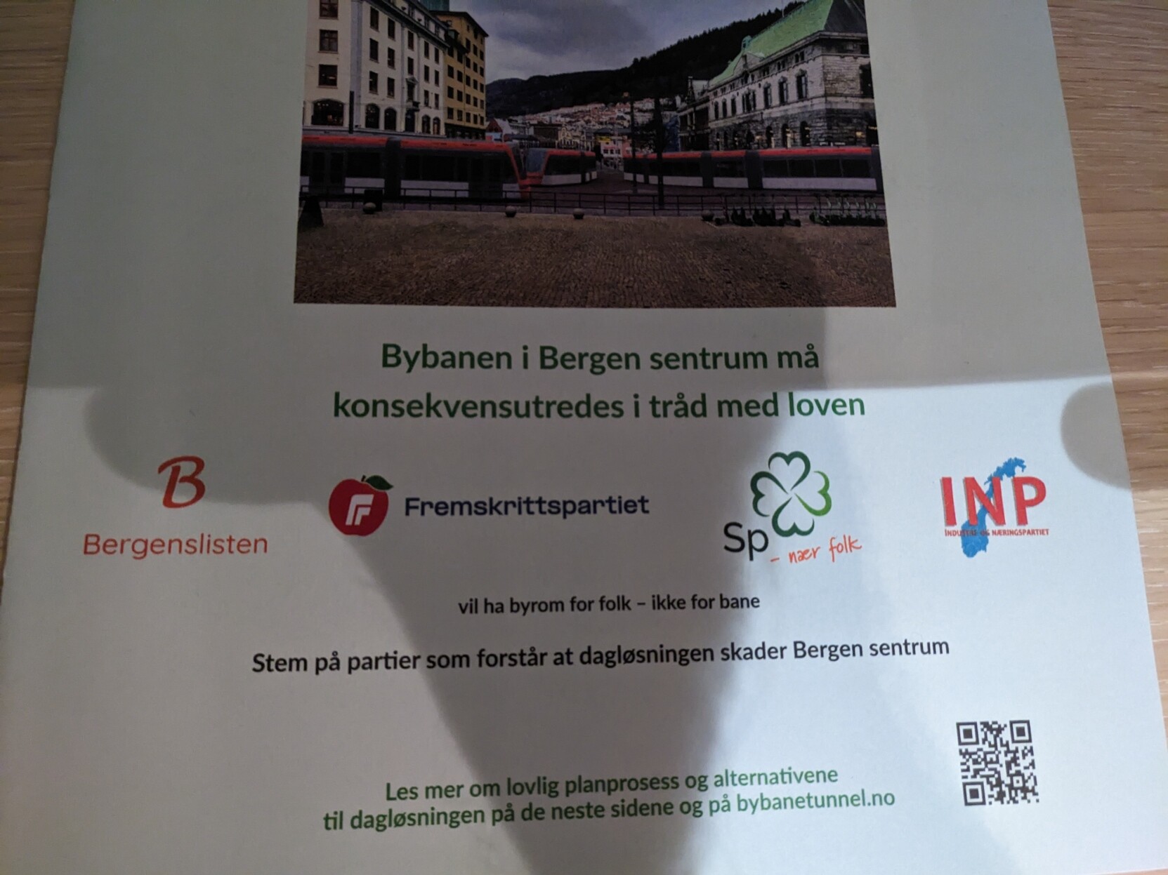 Papir med bilete, tekst, og logoar.

I toppen ser me bybane-visualiseringa av Torgallmenningen.

Tekst:
«Bybanen i Bergen sentrum må konsekevensutredes i tråd med loven»

Logoane til Bergenslisten, Fremskrittspartiet, Senterpartiet, og Industri- og næringspartiet.